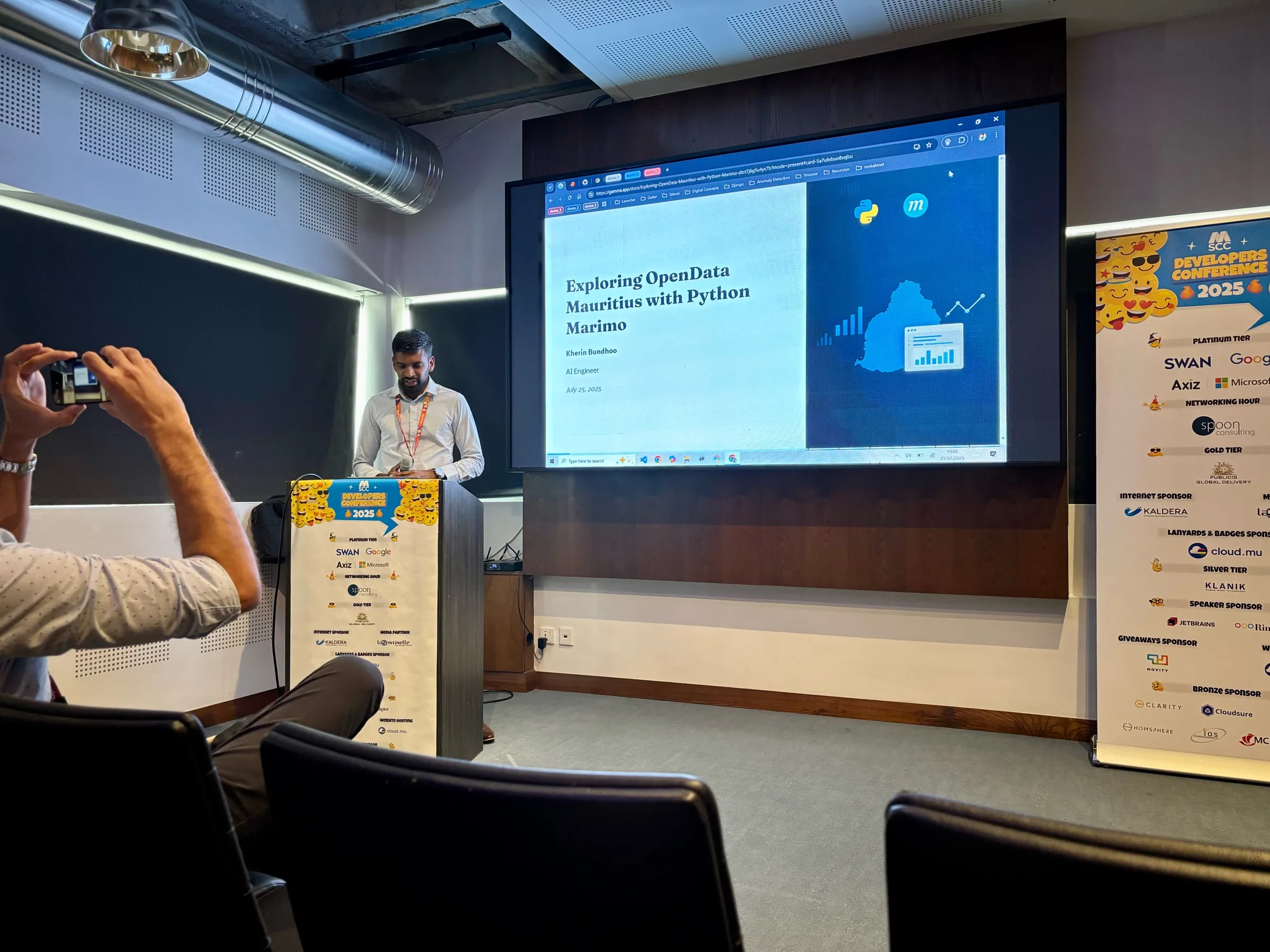 Kherin presenting on stage at Developers Conference 2025, with a slide reading 'Kherin Bundhoo, AI Engineer'