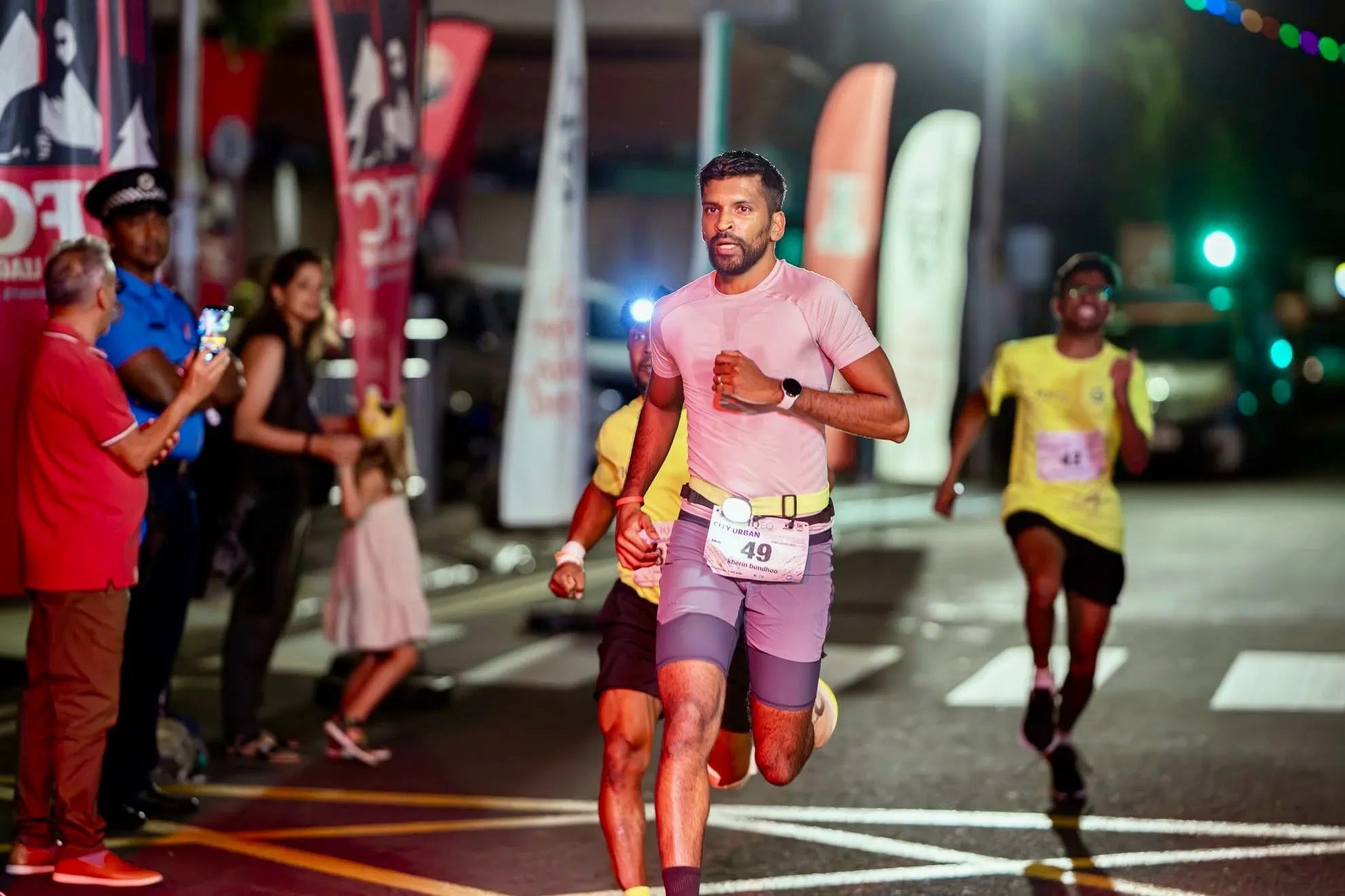Kherin running through a city street at night wearing bib number 49